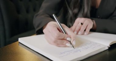 Ofisteki günlüğüne kalemle yazı yazan bir kadın. Evinde uzak bir işi, işi ve kariyeri olan meşgul bir iş kadınının çalışma stratejisi notları. Elle planlama ve uzaktan çalışma kavramı