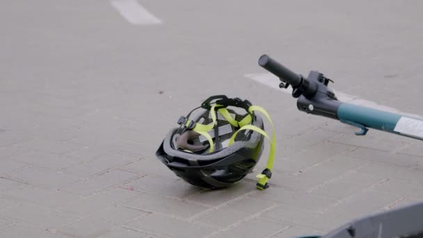 電動スクーターからの深刻な道路事故と住宅地の豪華な白い車の後にアスファルトで回転保護ヘッドヘルメットのクローズアップ 道路事故の概念 — ストック動画