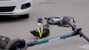 Trafik kazasının ayrıntıları var. Bir araba elektrikli scooterla birine çarptı ve koruyucu kask aşağı uçtu ve arka çanta. Arabanın parçaları asfalta düştü.
