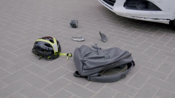 자동차와 스쿠터 사이의 사고의 교차로에서 포장에 떨어지는 자동차와 헬멧과 가방에 — 비디오