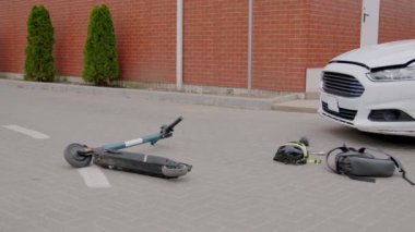 Bir araba ve elektrikli scooter arasındaki trafik kazası. Okul çocuğunun araba çarpması ve kaskının ve okul çantasının okulun yakınındaki bir kavşakta kaldırıma düşmesi..