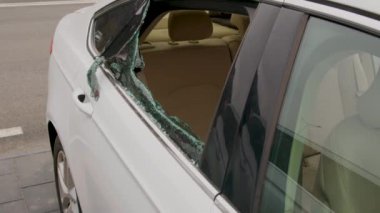 Otoparka park edilmiş parçalanmış bir arabanın yakın plan görüntüsü. Vandalizm eylemi ve bunun yol açtığı hasarı gösteriyor.