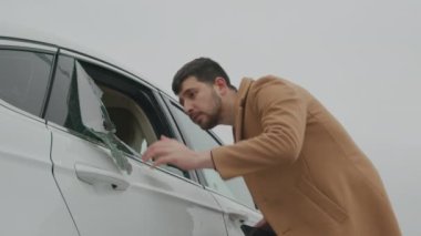 Şaşkın adam parçalanmış arabanın camını fark etti ve acil bir arama yaptı. Araba sahibi kırık pencereyi keşfediyor..