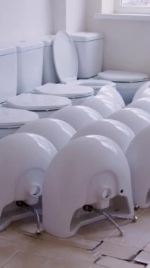 İnşaat alanlarında bir grup tuvaletin bulunduğu dikey oda videosu var. Bu porselen eşyalar, boş alanda amaçlarını bekleyen kolaylık ve işlevselliğin özünü somutlaştırıyor.