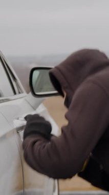 Araba hırsızı otomobil hırsızı dikey araç görüntülerini çalıyor. Araba hırsızı tarafından çalınan araba hırsızı. Gerçek araba hırsızı. Şehir sokaklarının güvenliğini tehdit eden ısrarcı bir gölge.