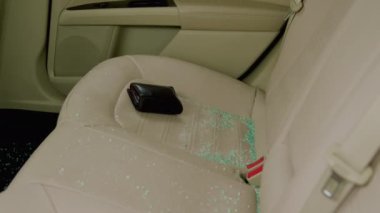 Suç sonrası cam kırıkları arabanın arka koltuğunu kirletiyor. Arka pencereden kırılan cam parçaları arka koltuğa saçılmış. Kırık cam kırıkları var.