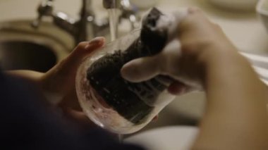 Titiz bir görevle meşgul olan kişi, şarap bardağını yıkar, şarap bardağının önemini fark eder. Aşçılık çabaları için temiz şarap kadehleri ve alınan her yudumun güvenliğinden emin olur.