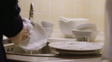 Mutfakta insan eli çabukça bulaşıkları yıkıyor ve gıda hazırlama ve tüketim bulaşıkları için hijyenik ortam sağlanmasındaki rolünü anlıyor. Ev mutfağında bulaşık yıka.