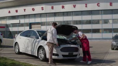 Otomobil tamircisi, araba tamir servisinde kaputu açık vites gösterme becerisini ustalıkla kullanır. Araba tamircisi oto tamircisi araba tamir servisinde çalışıyor.