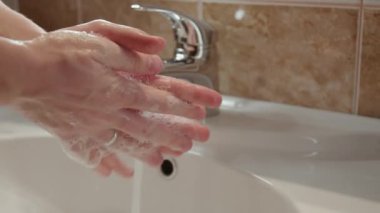 Kişi ellerini titizlikle akıntılı suyun altında yıkar yakın planda temizlik yapmanın önemini fark eder cilt yıkamanın saflığı hastalığın yayılmasını önler. İnsan lavaboda ellerini yıkar.