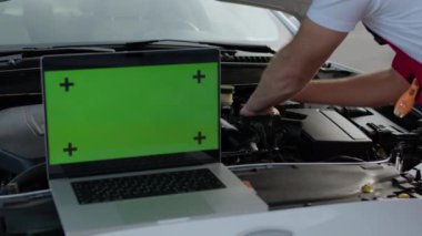 Yeşil krom anahtar ekranlı dizüstü bilgisayar kullanan otomotiv teknisyeni, otomotiv sanayii kroma anahtarında gelişmiş teşhis araçları ve onarım teknikleri kullanan aracı yeterince tamir ediyor