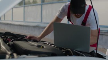 Otomotiv hizmet merkezinde tamirci kaputu açık, somut bir tamirci rolü olan arabaya ustaca bakar ve güvenilir araba tamir hizmetlerinin sağlanmasındaki önemini gösterir.