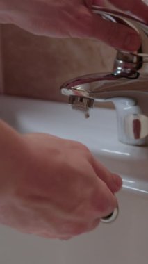 Suyun altında ellerini yıkayan kişi dikey videoyu kapatır ve kişisel hijyene yönelir. Her eksiksiz durulamada kişisel hijyen temizlik önceliği temizlikle mücadele mikropların kişisel hijyenle yayılmasını sağlar.