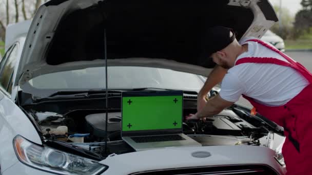 Mechanik Naprawia Zepsuty Samochód Pod Otwartym Laptopem Kaptur Zielony Ekran Filmik Stockowy