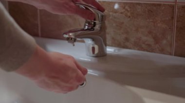 Ellerini yıkayan kişi lavabo akışı temiz su metalik musluk kişisel hijyen. El yıkama, ev banyosu, su temizliği, temiz su, el yıkama.