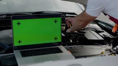 Kaput dizüstü bilgisayarının altında araba tamir teknisyeni yeşil ekran otomotiv tamir uzmanlığı atölyesi. Yeşil renk ekran mekaniği sorunları tanımlar, servis arabalarını çalıştırır