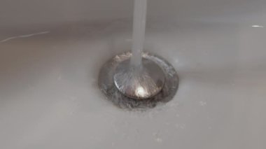 Saf su akıntıları lavabo deliği kişisel hijyen ev banyosu. Sıvı temizlik beyazı lavabo deliği boşaltma havzası hijyen uygulaması temizlik temizliği ev banyosu dökülüyor.