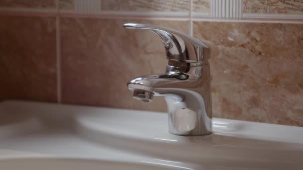 Wassertropfen Aus Kristallklarem Wasser Fallen Einen Glatten Wasserhahn Aus Keramik — Stockvideo