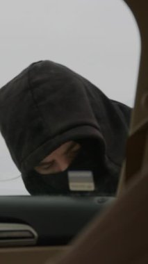 Araba hırsızı kapüşonlu hırsız güvenlik tehdidi oluşturarak başkasının mülkünü ihlal ederek araba kilidini kırıyor. Bu, araç sahiplerini bu tür suçlardan korumak için daha etkili güvenlik tedbirleri alınması gerektiğini vurguluyor