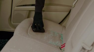 Araba hırsızı kırık cam kenarından bir şeyler çalar. İç mekan görünümlü vandalizm araç hırsızlığı. Hırsız, cam kırıklarının arasından eşyalarını kapıyor. Araba hırsızlığı, araba hırsızlığı.