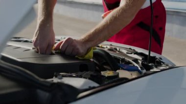 Araç yağı seviyesini kontrol eden kişi, açık kaput otomobil yağı denetim aracı onarım kontrolünden geçiyor. Tamirci, açık kaput otomotiv hizmetinin altındaki araba yağı seviyesini inceliyor.