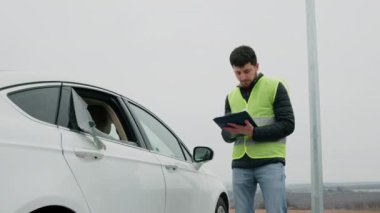 Erkek müfettiş, hırsızlıktan sonra sigortalı aracın uğradığı hasarı içeren bir dosya hazırlıyor. Bilerek kırık camlı beyaz bir araba. Sigorta şirketleri için kavram