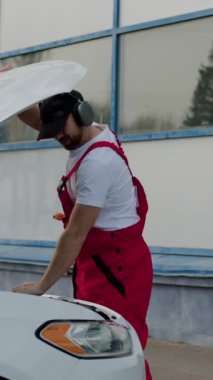 Prestijli bir araba servisi çalışanı, kulaklıklarında kulaklıkla dans ediyor. Genç ve modern bir araba tamircisi tamir edildikten sonra arabanın kaputunu bir bezle siler. Hikaye için video