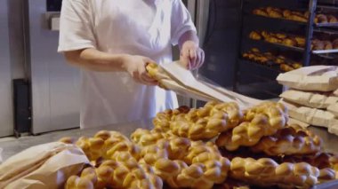 Fırıncı kekleri fırından çıkardı ve ekolojik kağıt paketlere koydu. Tam buğday ürünleri olan küçük bir pastaneden görüntü. Küçük başarılı fırın işi