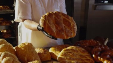 Baker 'ın elinde mayasız geleneksel ekmek var. Sağlıklı, doğal ekmek, geleneksel tariflere göre yapıldı. Aile şirketinin küçük bir pastanesinde ev yapımı köy ekmeği ile yakın plan..