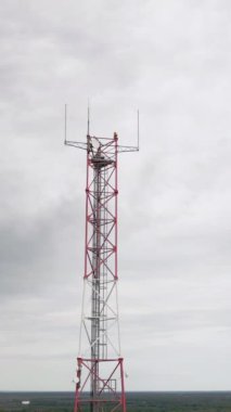 Dikey video. Mobil alıcı ve verici anten kulesi, mavi gökyüzü olan anten kulesi. Gökyüzü arkaplanlı anten ya da iletişim anten kulesine yakın çekim