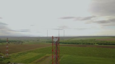 Yeşil tepelerin ve gökyüzünün arkasındaki baz istasyonu. Telekomünikasyon ve hücresel iletişim ekipmanları. Mobil kule kurulumu. Cep telefonu sitesi ve telekomünikasyon merkezi.