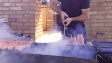 Şef, kırmızı somon balığı şişini diğer tarafa fırında pişirmek için çeviriyor. Arkadaşlarla piknik. Arkadaşlarla yaz barbeküsü. Izgara balık. Fırında pişmiş ve ızgara somon balığı. Açık hava ızgarası.