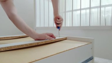 Müstakbel bebek için beşiği bir aletin yardımıyla birleştiren bir adamın elleri yakın plan görüntüsü. Müstakbel baba, yeni doğan bebek için odayı dikkatlice hazırlıyor. Parlak bir odadan samimi bir resim.