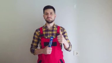 Adam ruh seviyesinin yardımıyla bir duvar prizi kurdu. Elektrikçi kameraya gülümsüyor ve yeni yenilenmiş bir apartmanın elektrik tesisatını bitirdikten sonra süper işareti gösteriyor..