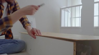 Adam beyaz ahşap bir mobilyayı söker ve bir aletle çivileri söker. Babam bebekler için bir karyola söker ve onu bir uyku yatağına çevirir. Mobilya kurulumu