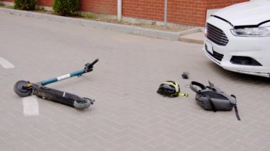 Elektrikli scooter kaskın ve sırt çantasının yanındaki kaldırımda yatıyor. Sahne, araba ile ciddi bir çarpışma sonrasını gösteriyor. Çarpmanın yıkıcı sonuçları