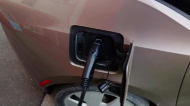Şehirdeki halka açık şarj istasyonuna bağlı modern elektrikli araba. Araç, uzun mesafeli seyahatler için uygun motor çalışması için elektrik alıyor