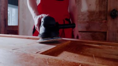 Usta öğütücüye yaklaştı ve iş için aletleri eline aldı. Uzman, yüzeyi düzleştirme ve ahşap yüzey kusurlarını kaldırma çalışmalarına başladı