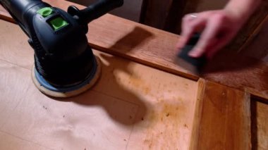 Marangoz ahşap yüzeyi neredeyse kapatıyordu. Ahşap işçisi zımparalama işlemi başlamadan önce kapı kenarlarını temizler