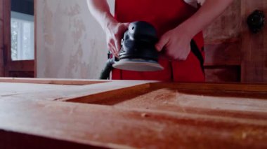 Elinde öğütücü olan ahşap işçisi kapıdaki aletleri yerleştirdi. Tecrübeli uzman, ahşabı parlatarak pürüzsüz ve hatta maddi yüzeye ulaşır