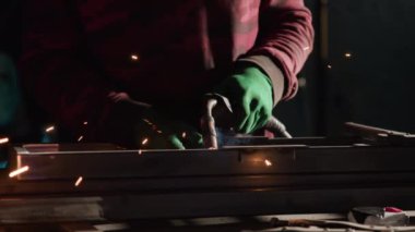 Demirci, güçlü inşaatı sağlayan metal merdiveni rafine ediyor. Eldivendeki metal işçisi, güçlendirilmiş dayanıklılık için kaynakçıyı kullanarak parçaları hassasiyetle kaynaştırıyor.