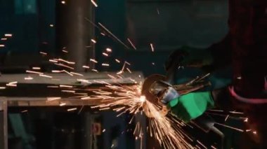 Üniformalı bir adam öğütücüyle yüzeye çıkıyor ve parıldıyor. Demirci, geniş atölyedeki gereksiz tümsekleri ortadan kaldıran metal detay kenarını parlatıyor