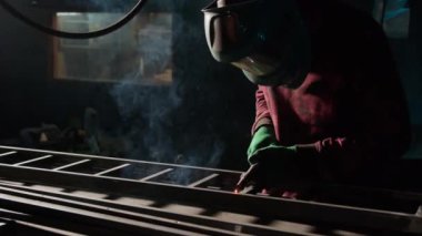 Demirci merdiven iskeletinde lapa lapa kaynakçısı işletiyor. Kaynak kasklı metal işçisi atölyedeki pürüzlü noktaları ortadan kaldırıyor