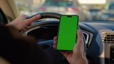 Adam akıllı telefonu elinde tutup araba paylaşım uygulamasına bakıyor. Erkek sürücü, modern hizmet sunan araç kiralama teklifleri arıyor
