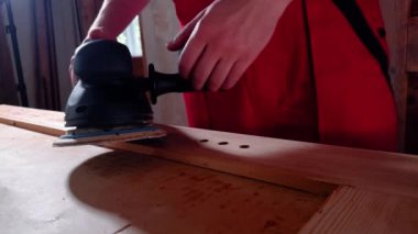 Tahta işçisi elektrikli zımpara makinesini elinde tutmaya başlıyor. Uzman tezgaha yürür ve öğütücü ayarlama mekanizmasını harekete geçirir