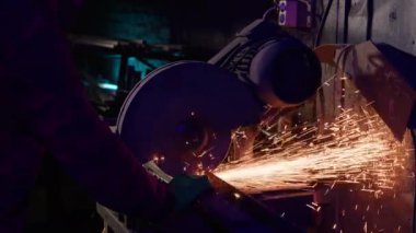 Yüzey öğütücüsü, demirci işyerinde kıvılcımlar üretir. Aşındırıcı tekerleği olan endüstriyel makine metal parçaları keskinleştiriyor.