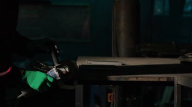 Demirci tezgahta duran metal yüzeyi parlatır. Eldivenli adam, gereksiz yükseklikleri ve kusurları ortadan kaldıran materyalleri işliyor.