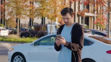 Adam araba paylaşım aracının yanında duruyor ve ödemeyi telefonla yapıyor. Erkek, araba kiralama öngörü gezisi için güvenli çevrimiçi işlem sağlar