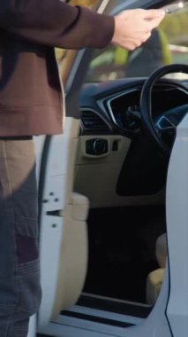 Akıllı telefonlu araba paylaşan müşteri direksiyon başına geçer. Adam sürücü koltuğuna geçer ve otomobil motorunu dikey çekime hazırlar.