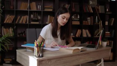 Kadın titizlikle kalın bir kitap okuyor. Kesinlik için kurşun kalemle. Esmer öğrenci kampüs kütüphanesinde okurken işine konsantre oluyor.